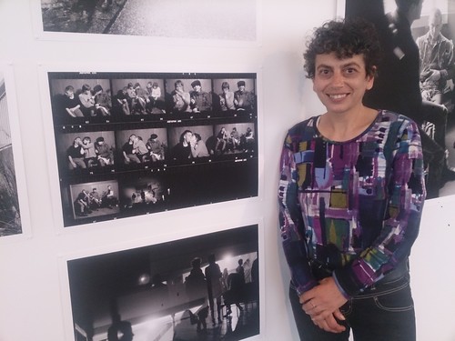 Sophia standing in front of a photograph taken in 1983 of her (seated left wearing a dark hat) and her friends at the Caledonian Hall.